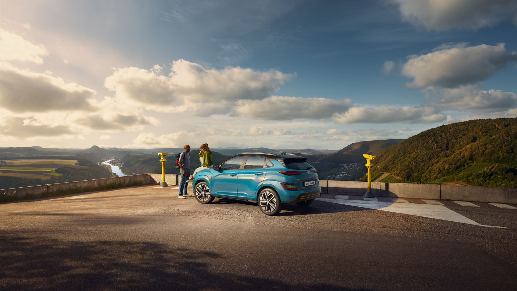 The new Hyundai Kona Electric standing in a parking lot with a great view over the country side.